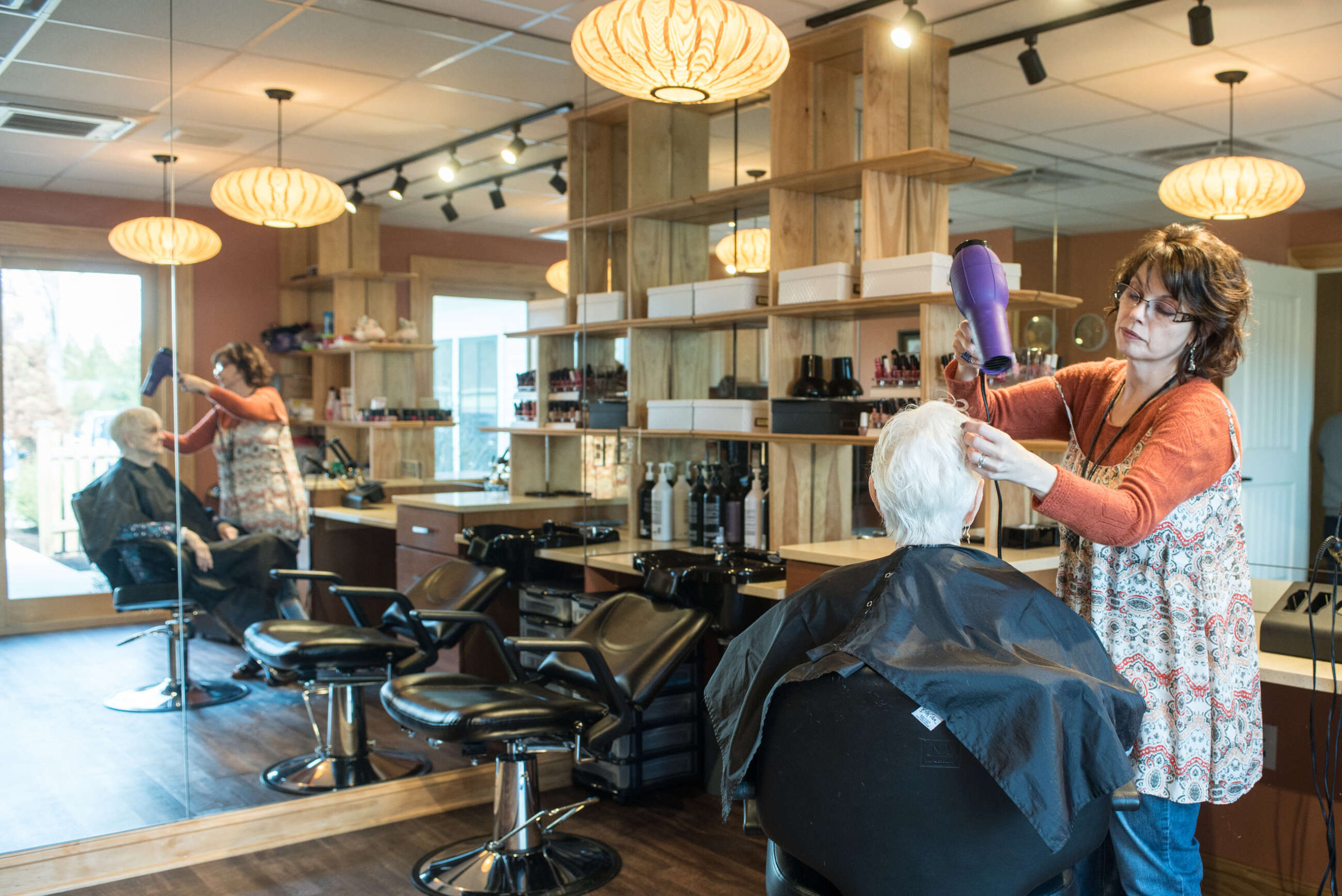 A woman styling a resident's hair in the salon