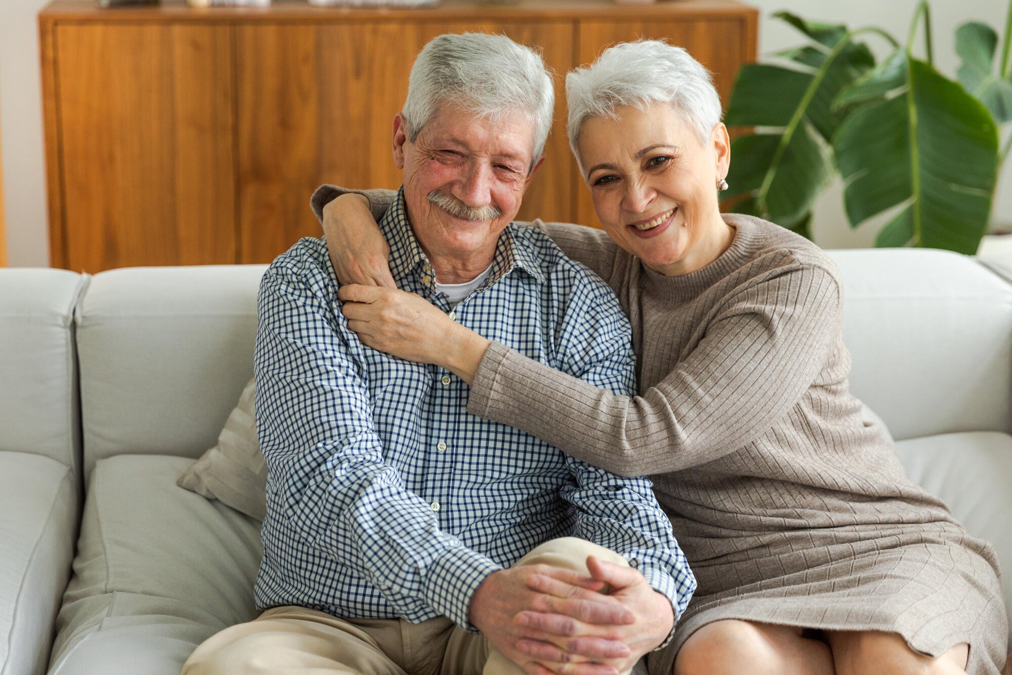 Two smiling seniors sitting on a couch