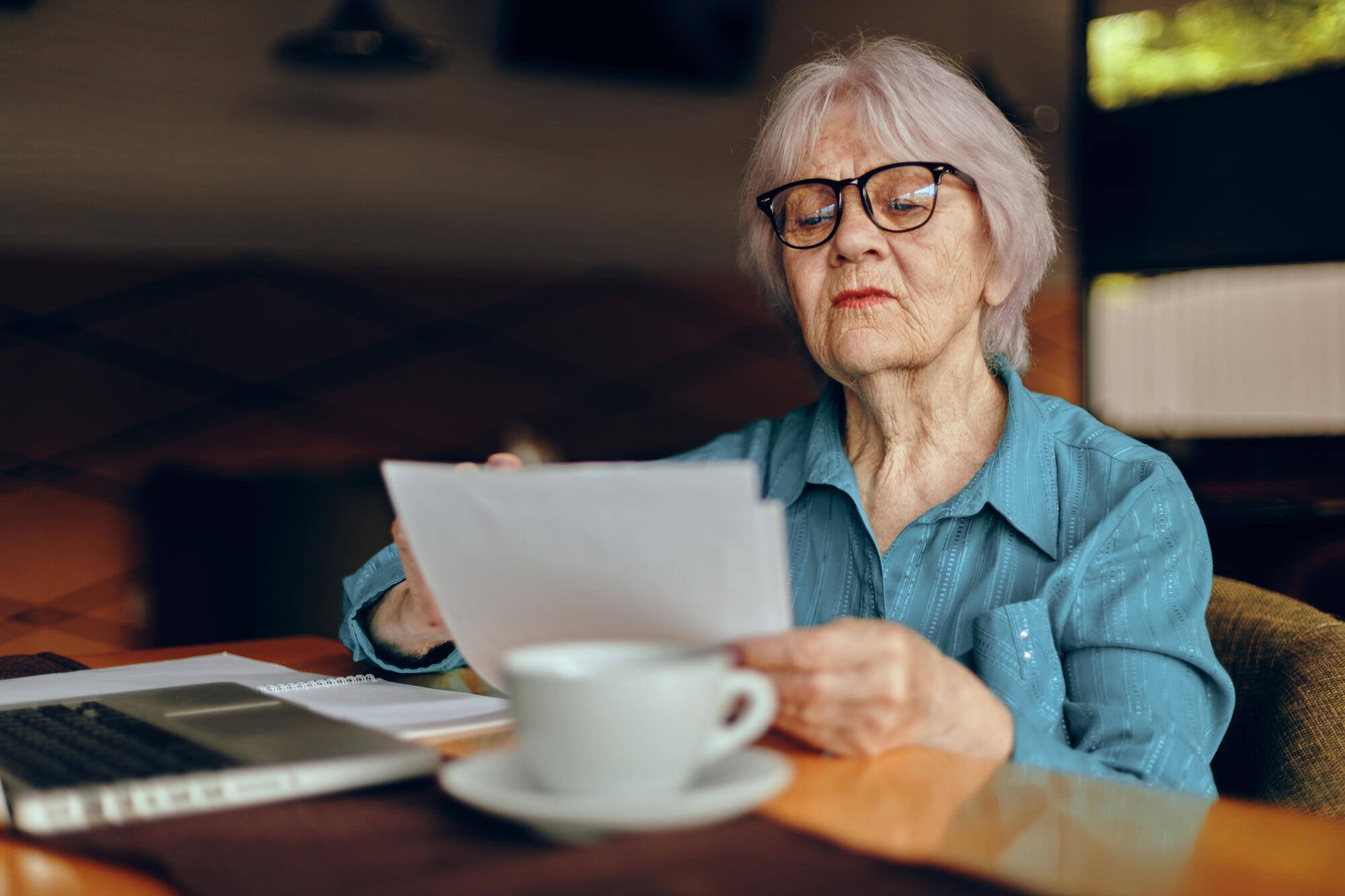 Senior woman reading papers at a table