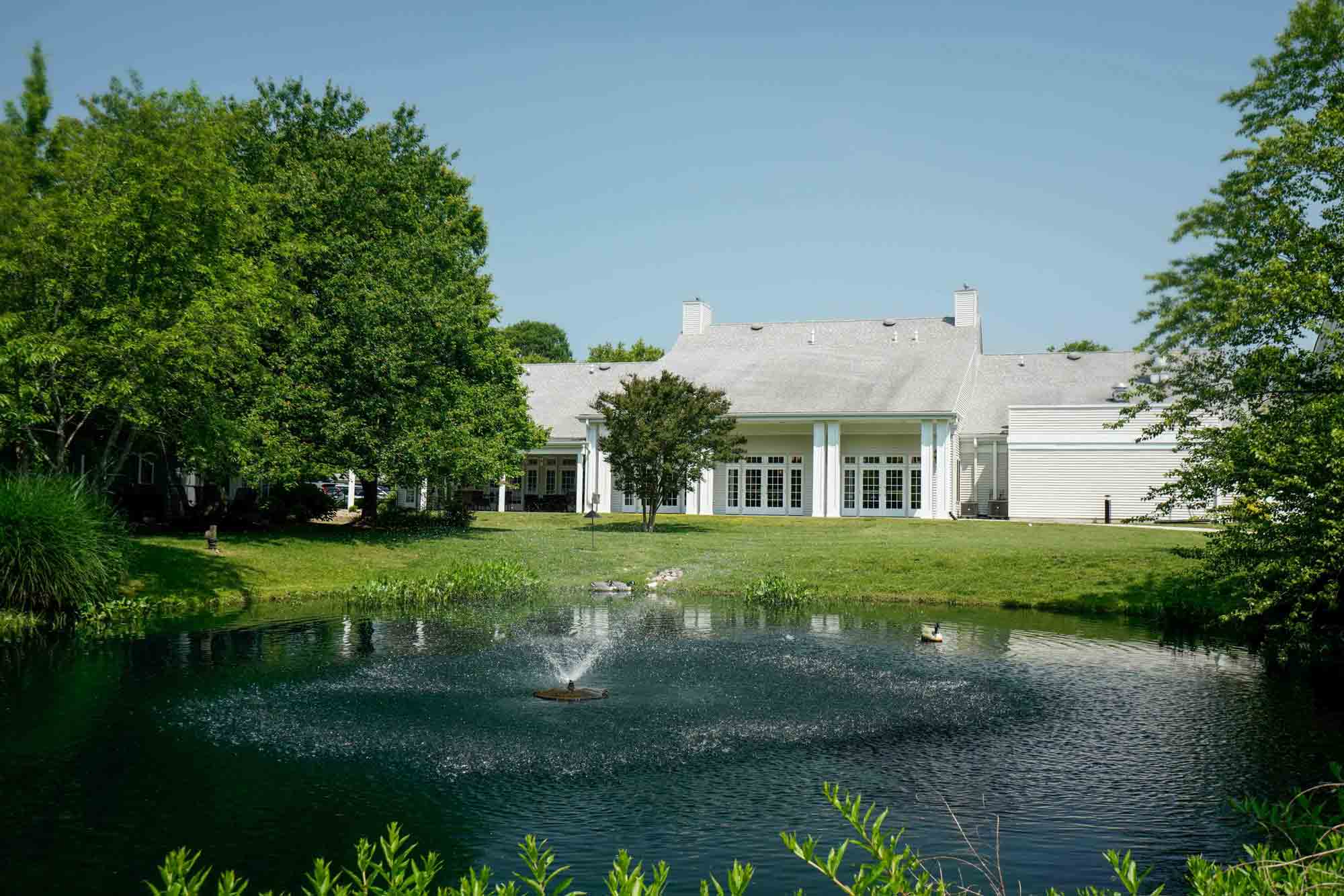 Exterior view of the facility with pond and trees