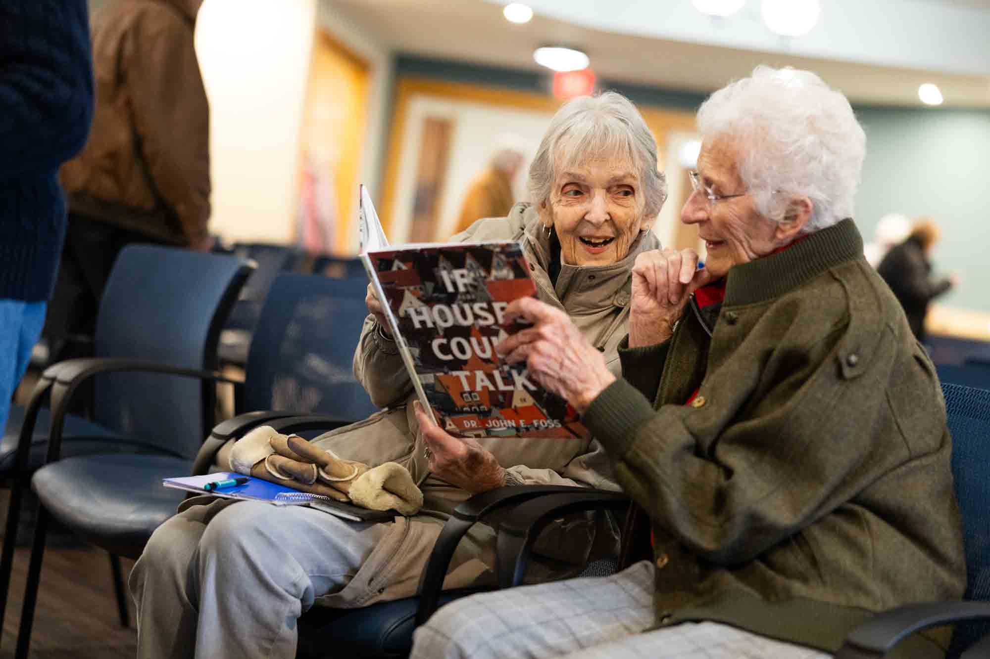 Two elderly women enjoying a book together
