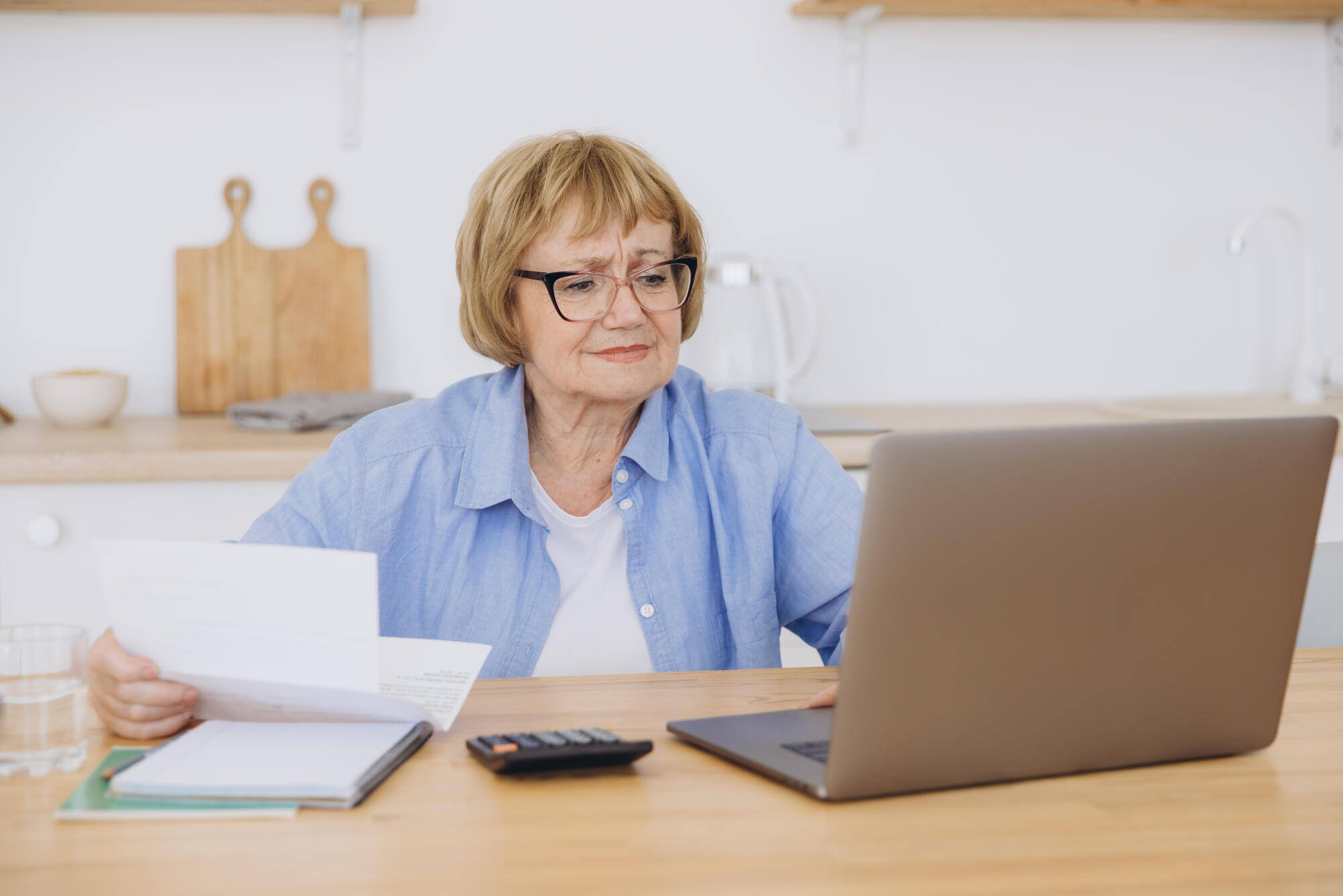Senior woman using a laptop at a kitchen table