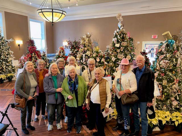 Residents posing by decorated Christmas trees in a common area