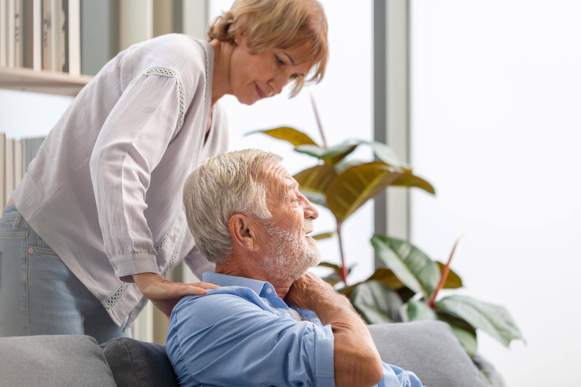 A caregiver assisting an older adult in a cozy living area