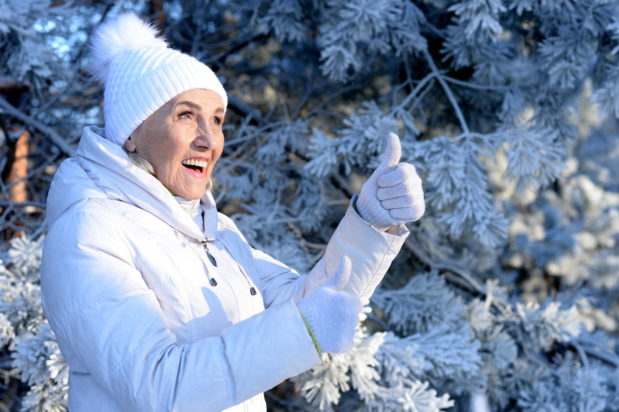 Senior woman smiling outdoors with thumbs up