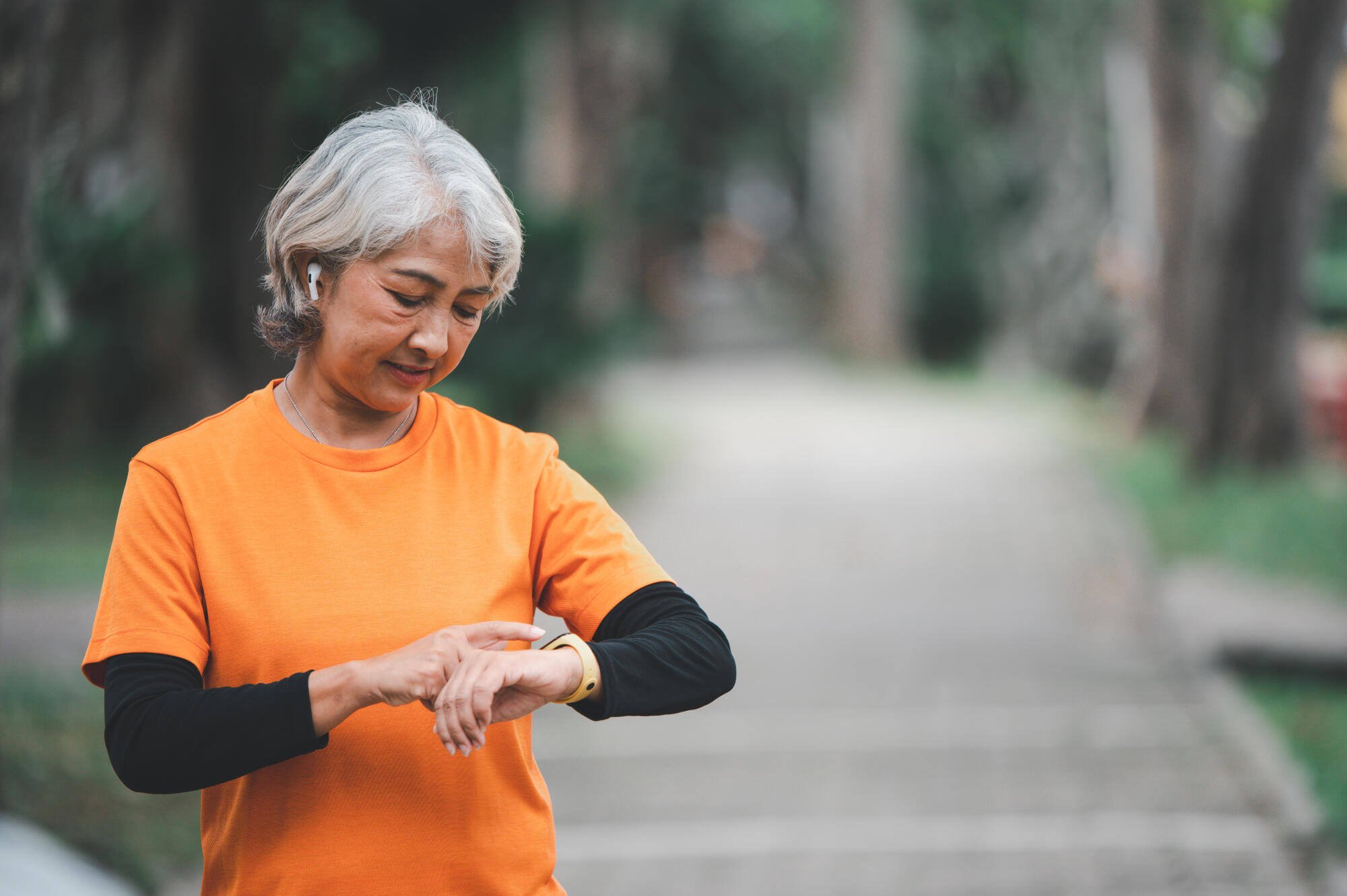Woman checking her watch in a garden path