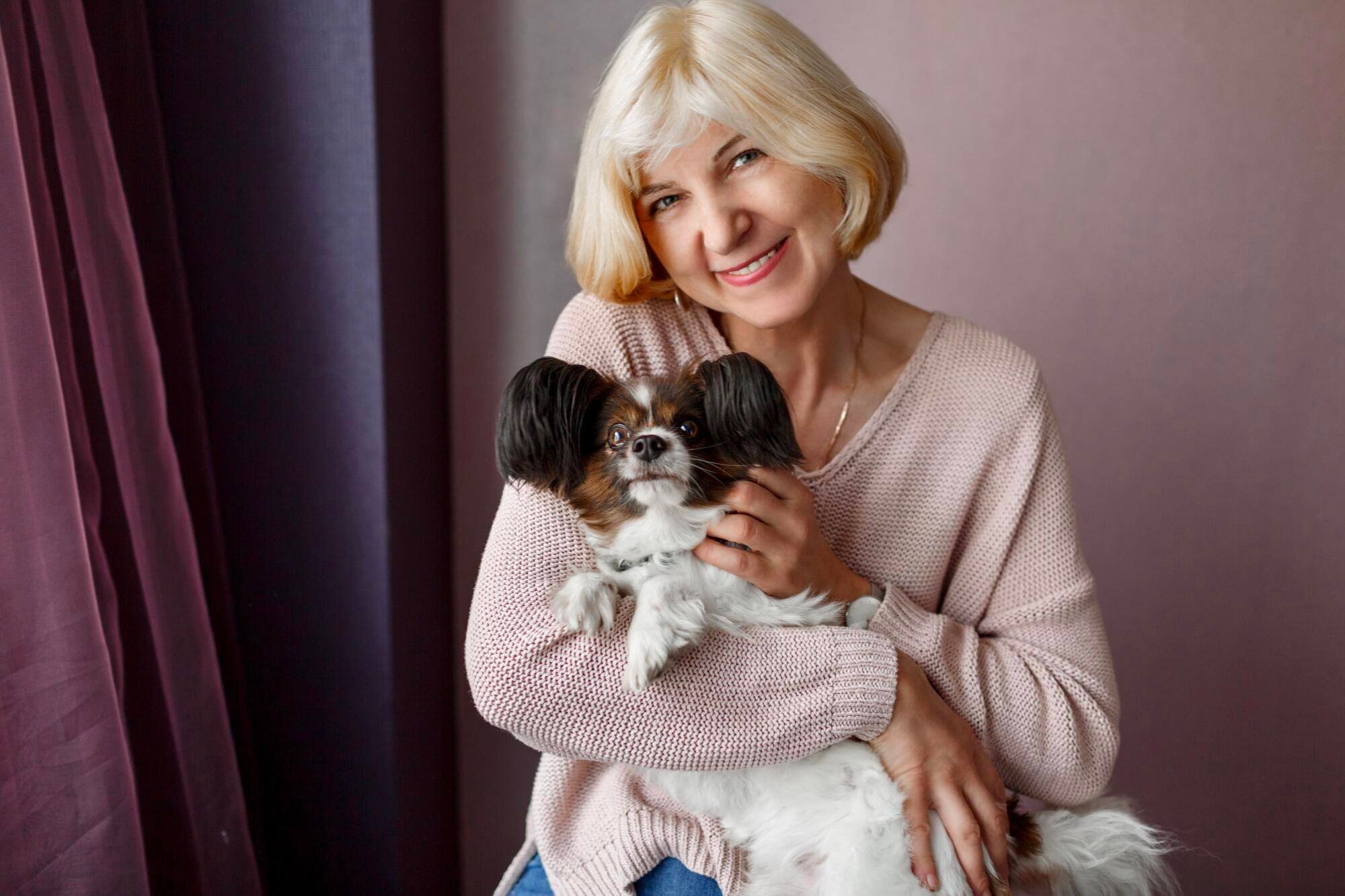 Senior woman smiling while holding a small dog