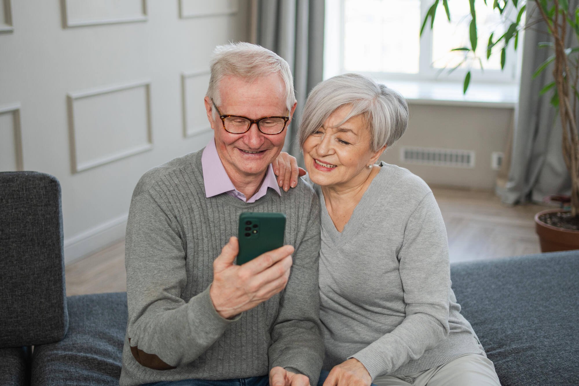 Older couple smiling while looking at a phone