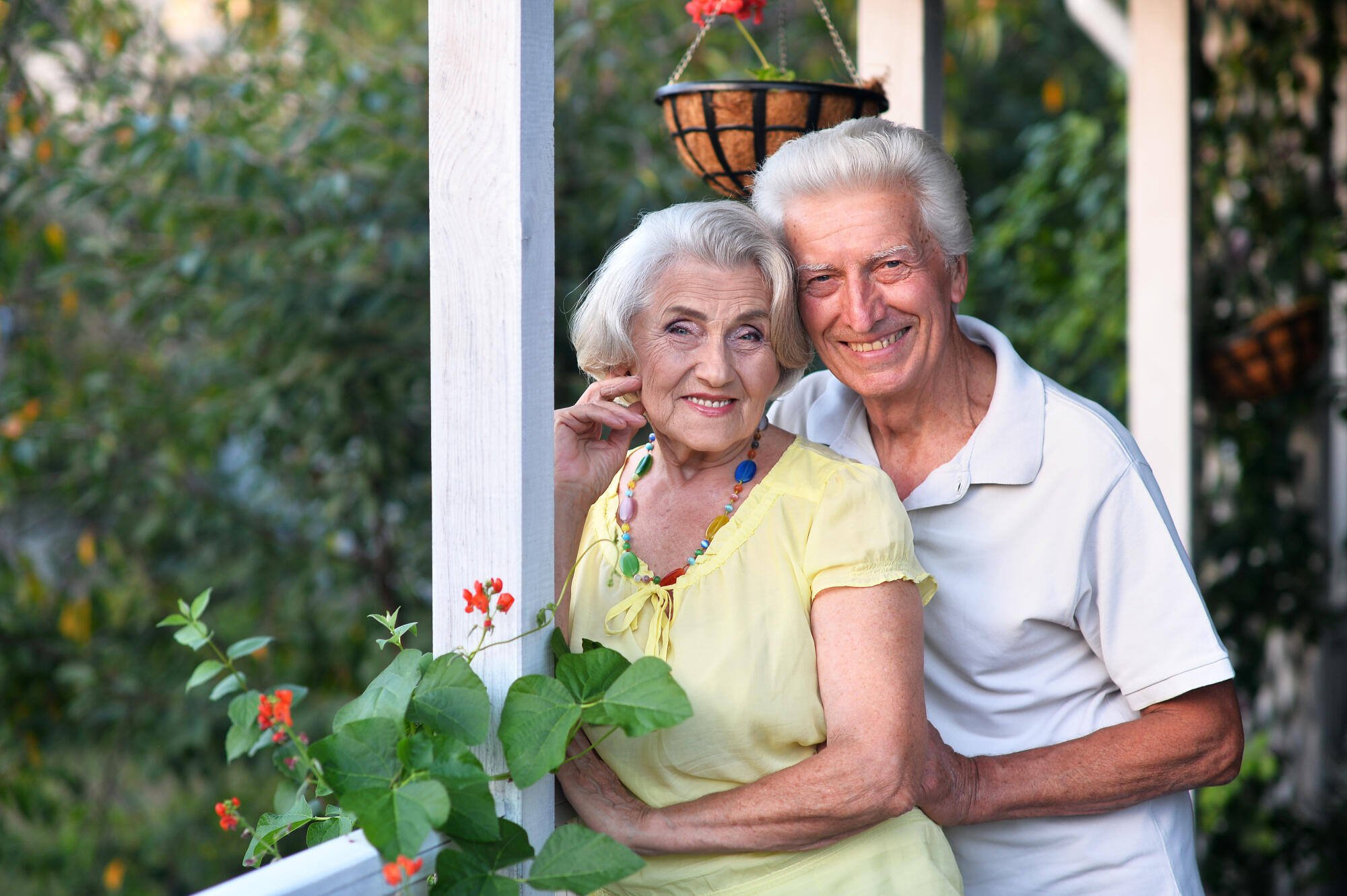 Senior couple smiling on a porch with plants