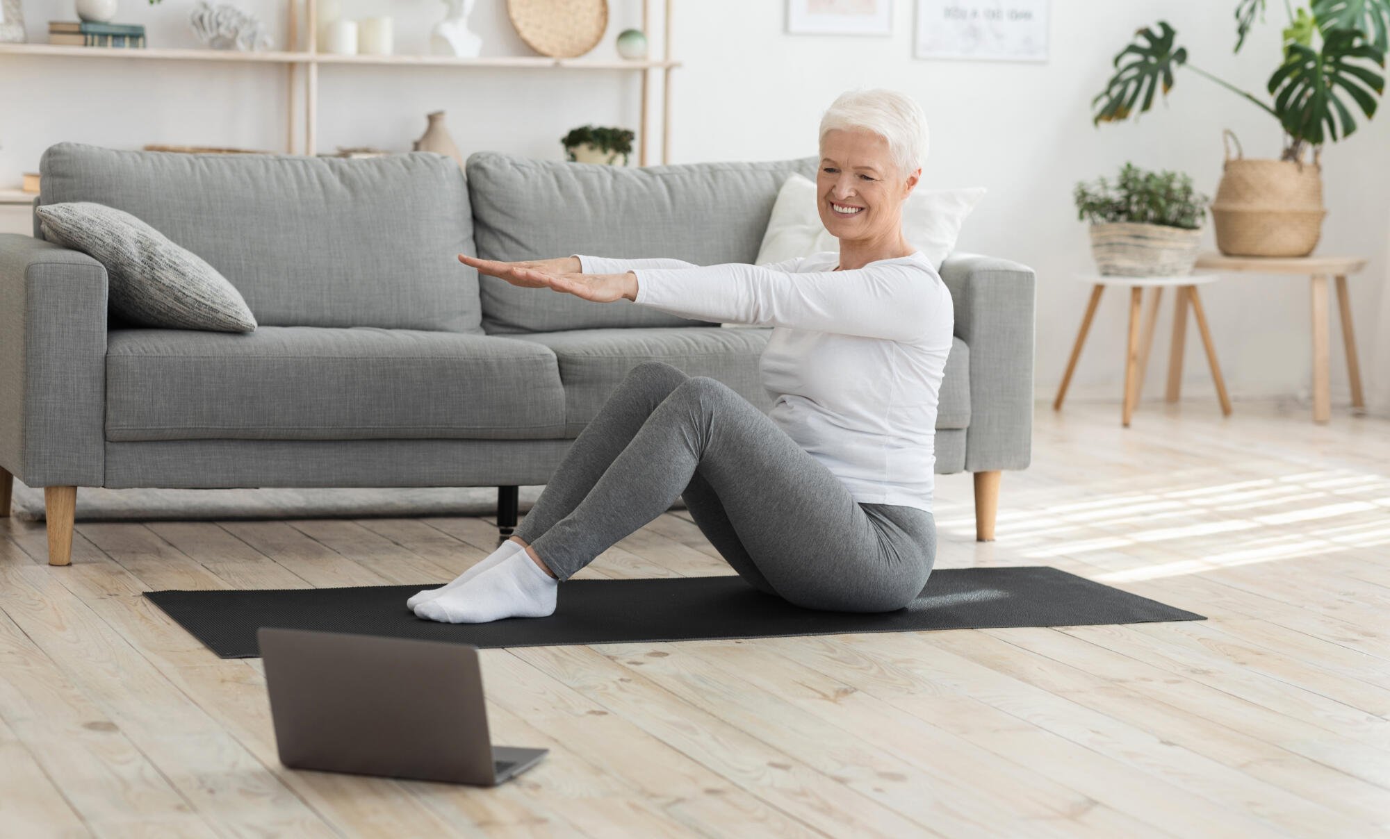 Senior woman exercising at home on a yoga mat