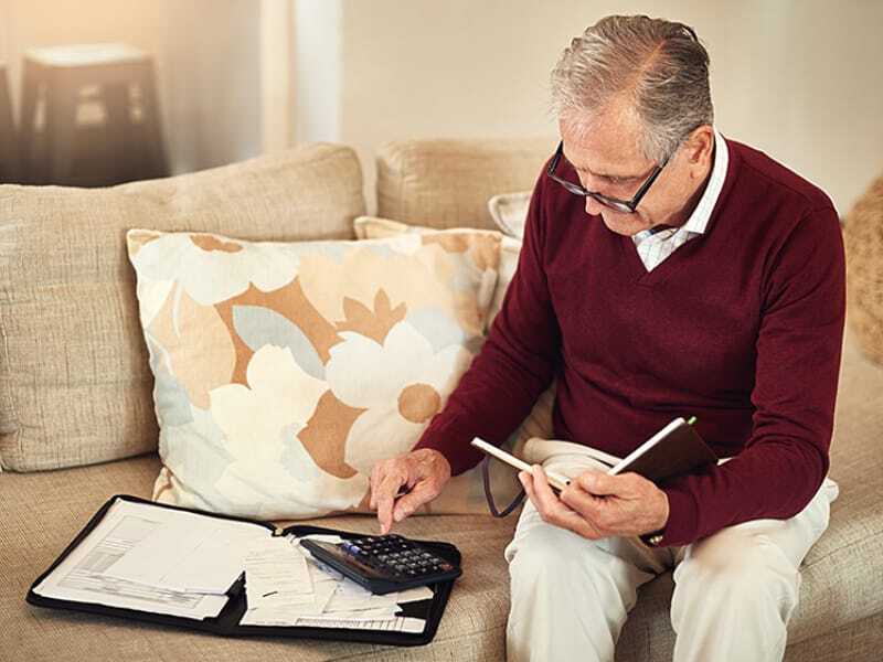 A senior man using a calculator at home