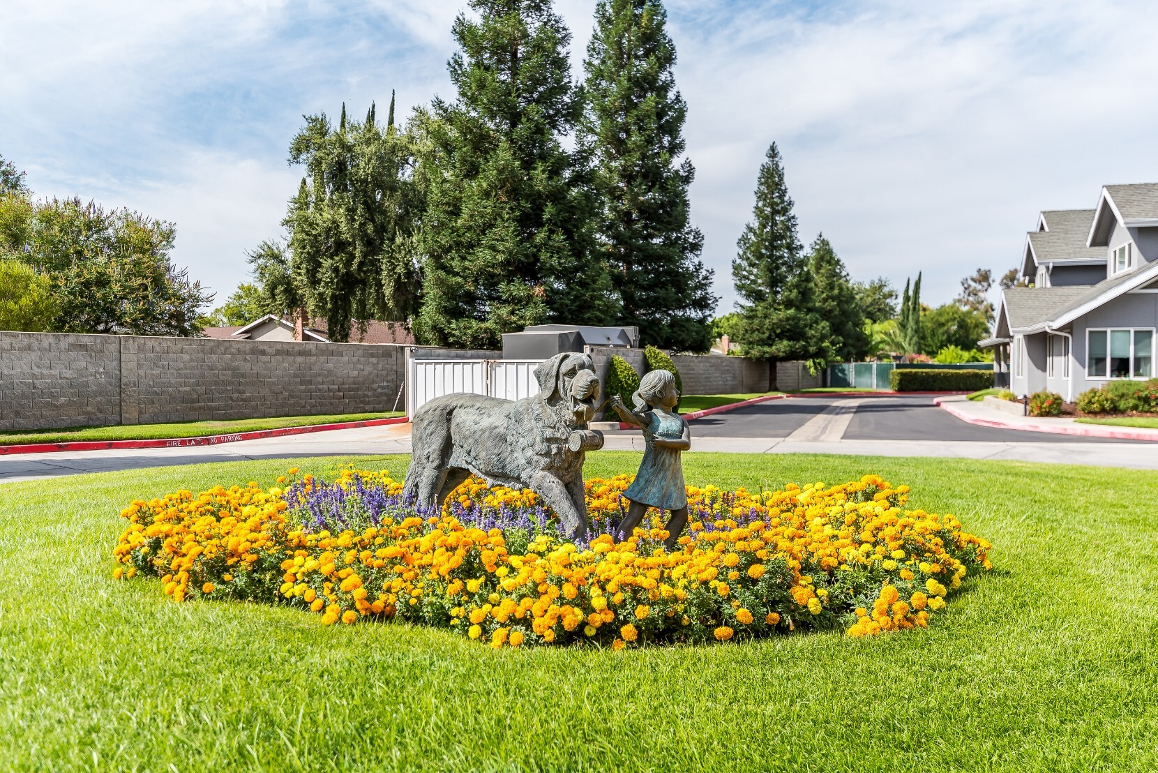 Statue of a child with a dog surrounded by flowers