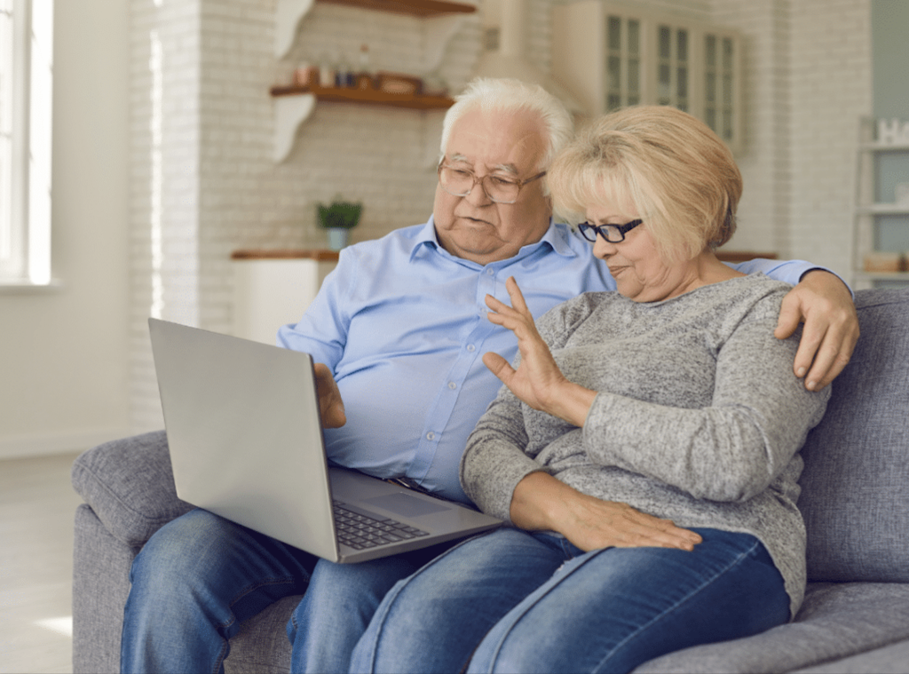 Two seniors engaging with a laptop in a cozy living room