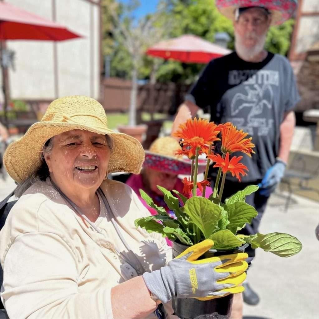A resident planting flowers in an outdoor garden