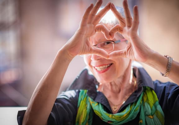 Resident making a heart shape with hands and smiling