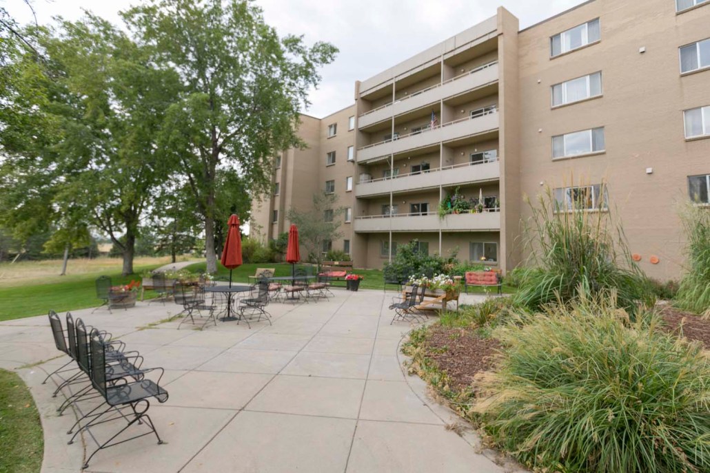 Outdoor seating area with gardens and building in background