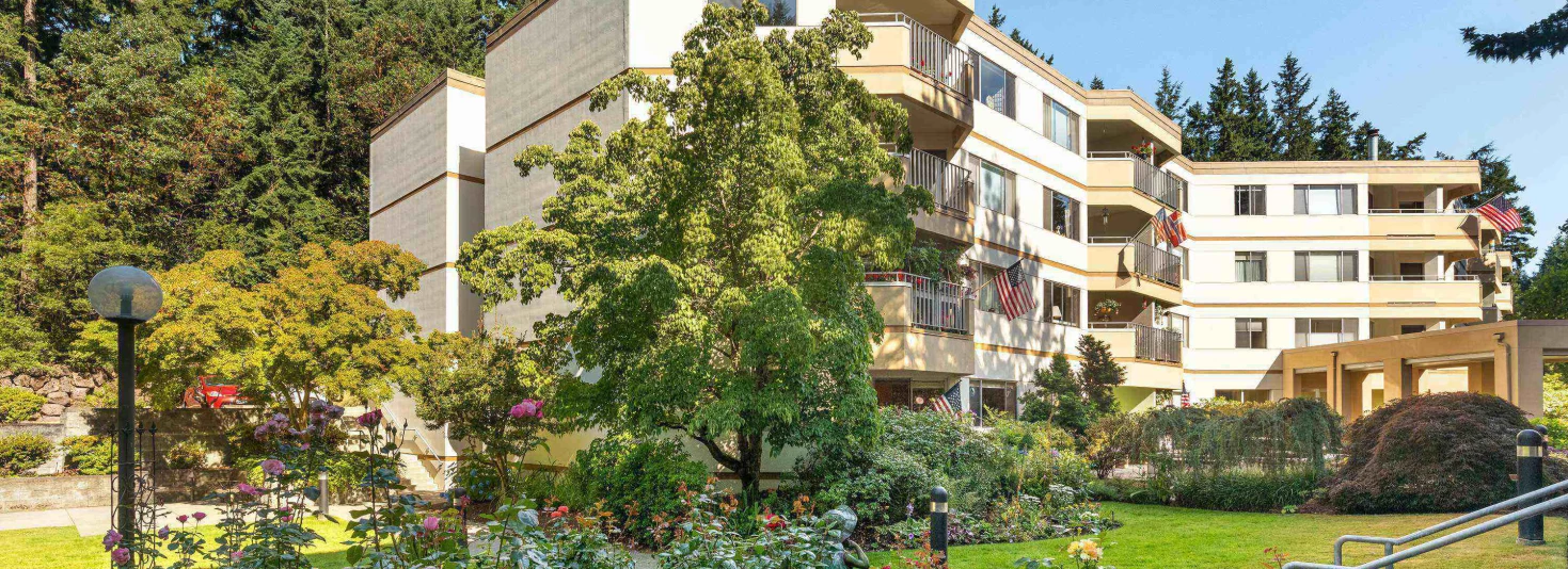 Exterior view of a senior living facility surrounded by gardens
