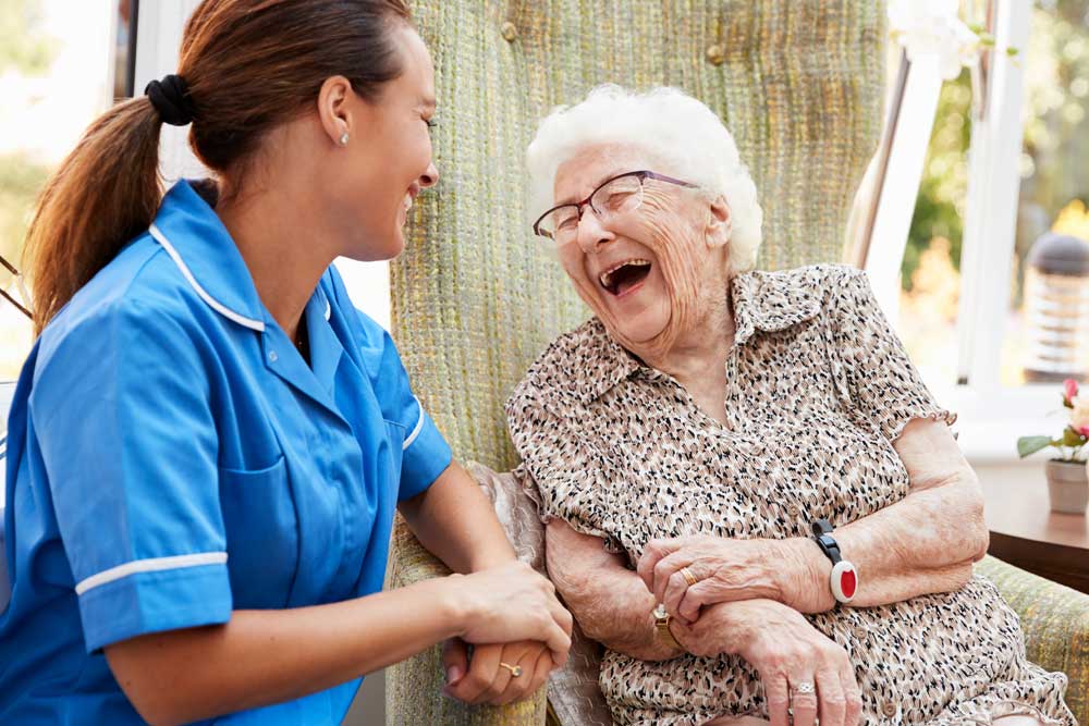 A caregiver laughing with a resident in a cozy setting