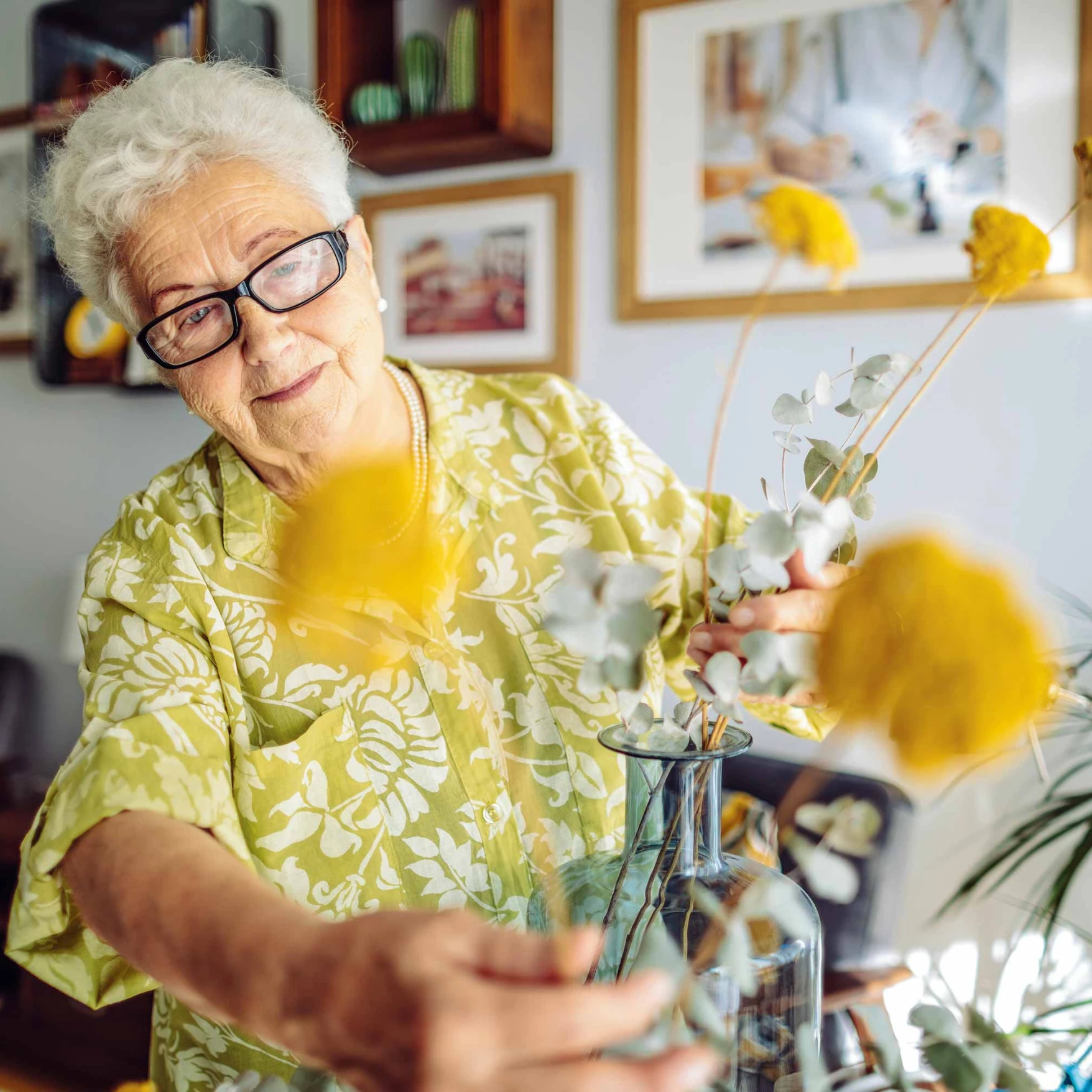 Senior woman arranging flowers in a bright room