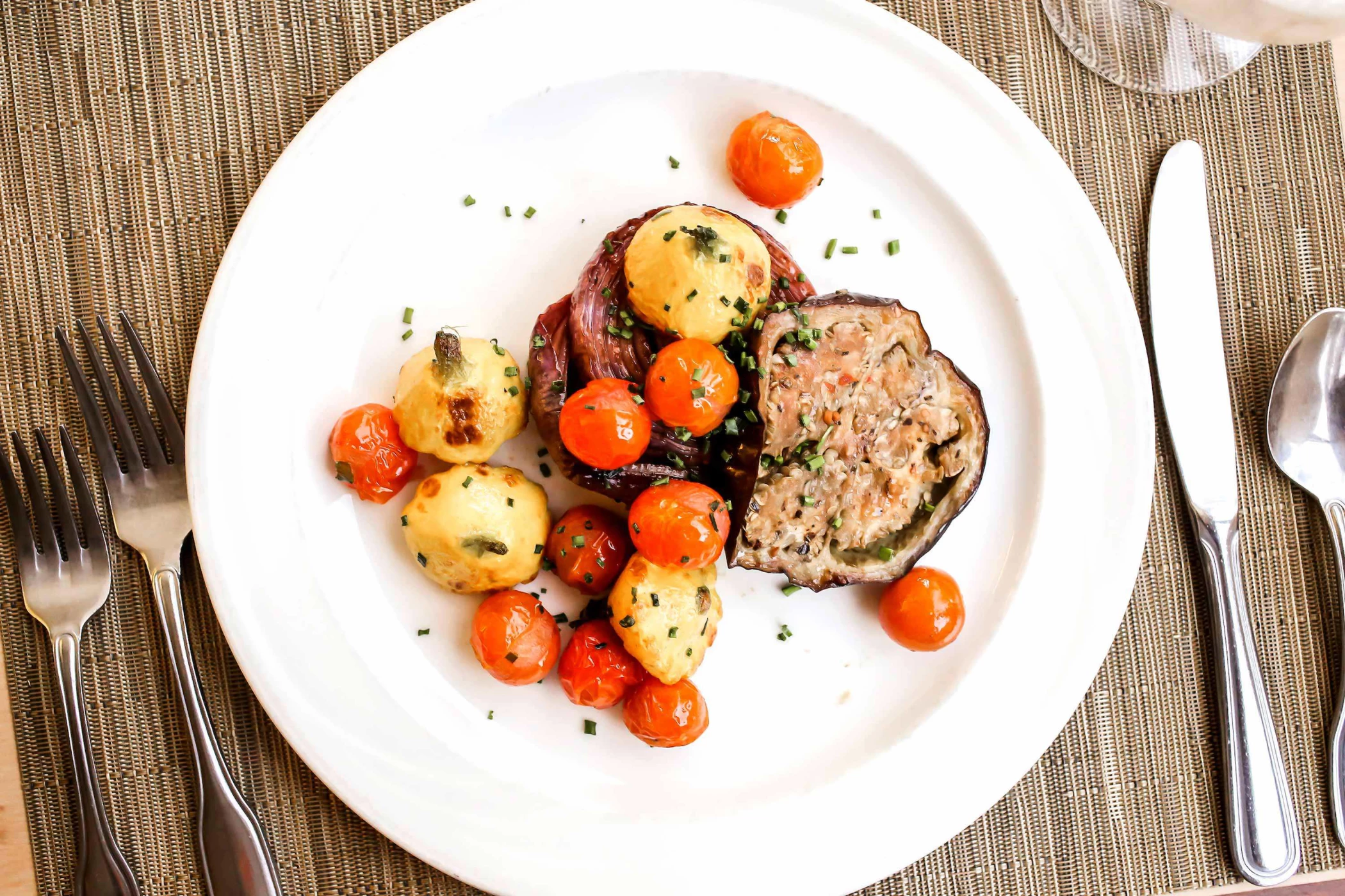 A plated meal featuring meatloaf, potatoes, and roasted tomatoes