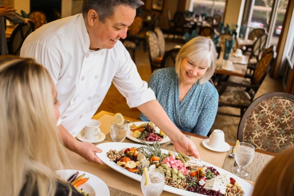 Chef serving a food platter to residents in the dining room