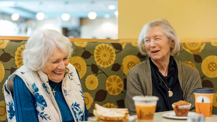 Two residents enjoying food and laughter in a dining area