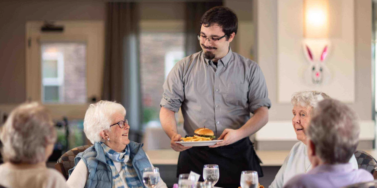Staff serving meals to residents in a dining area
