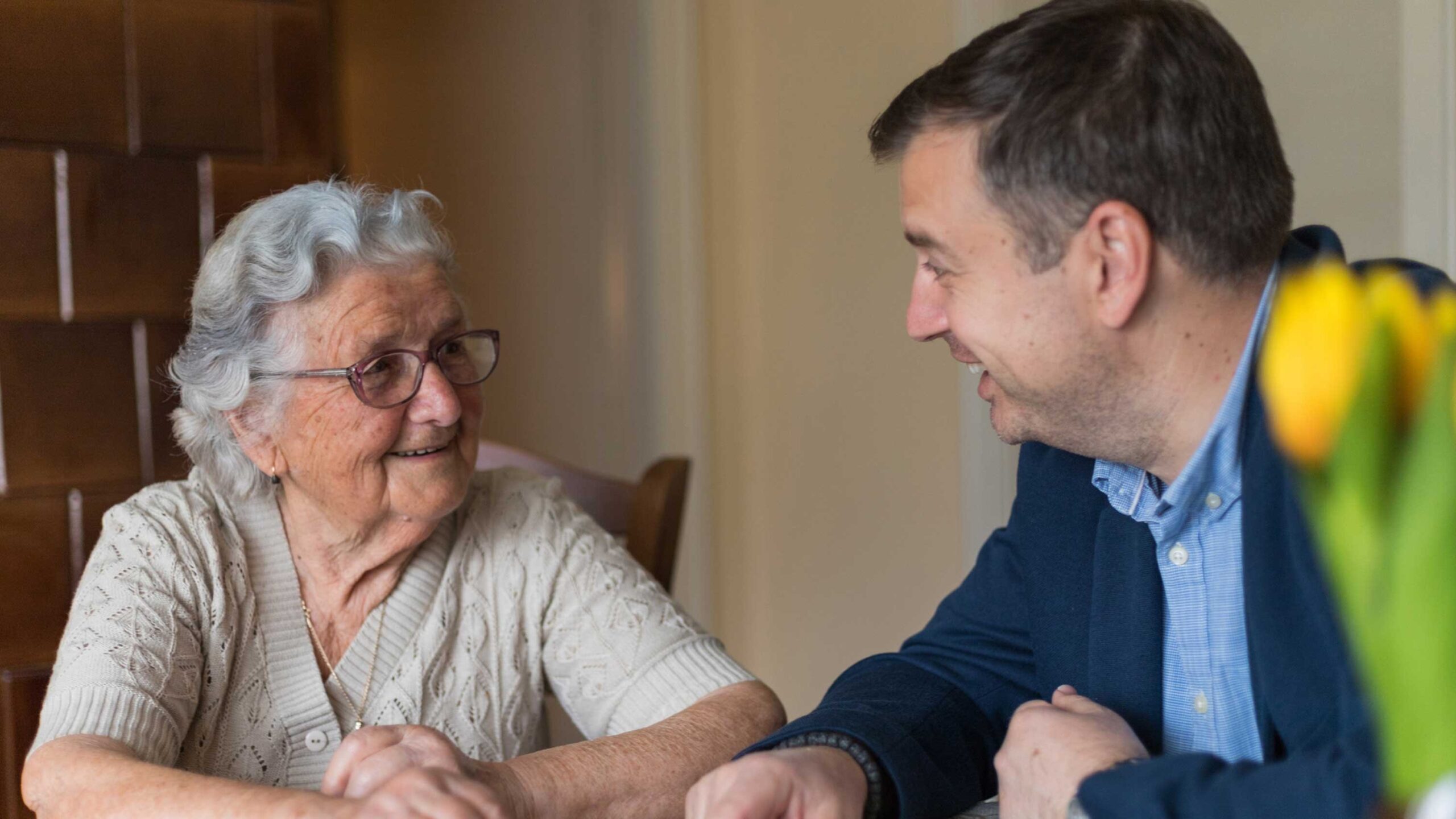 An elderly woman smiling while talking to a man