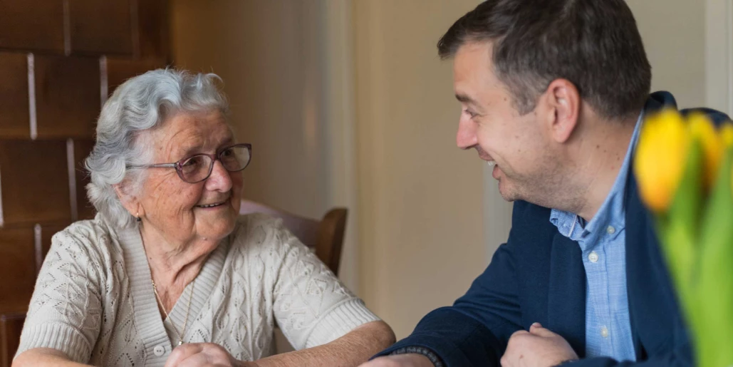 A resident smiling with a staff member in a cozy space