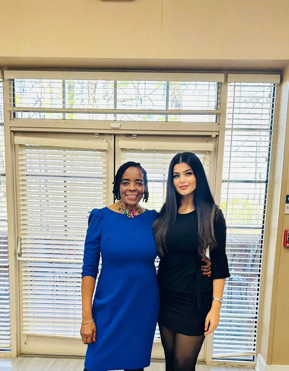 Two women posing in a common area of a facility.