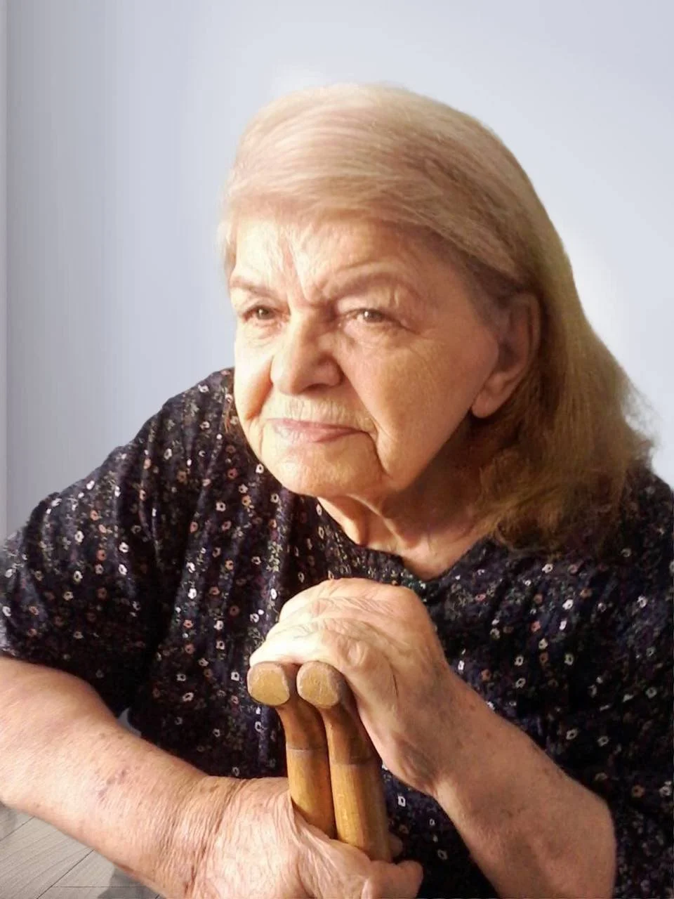 Elderly woman holding a cane, indoors.