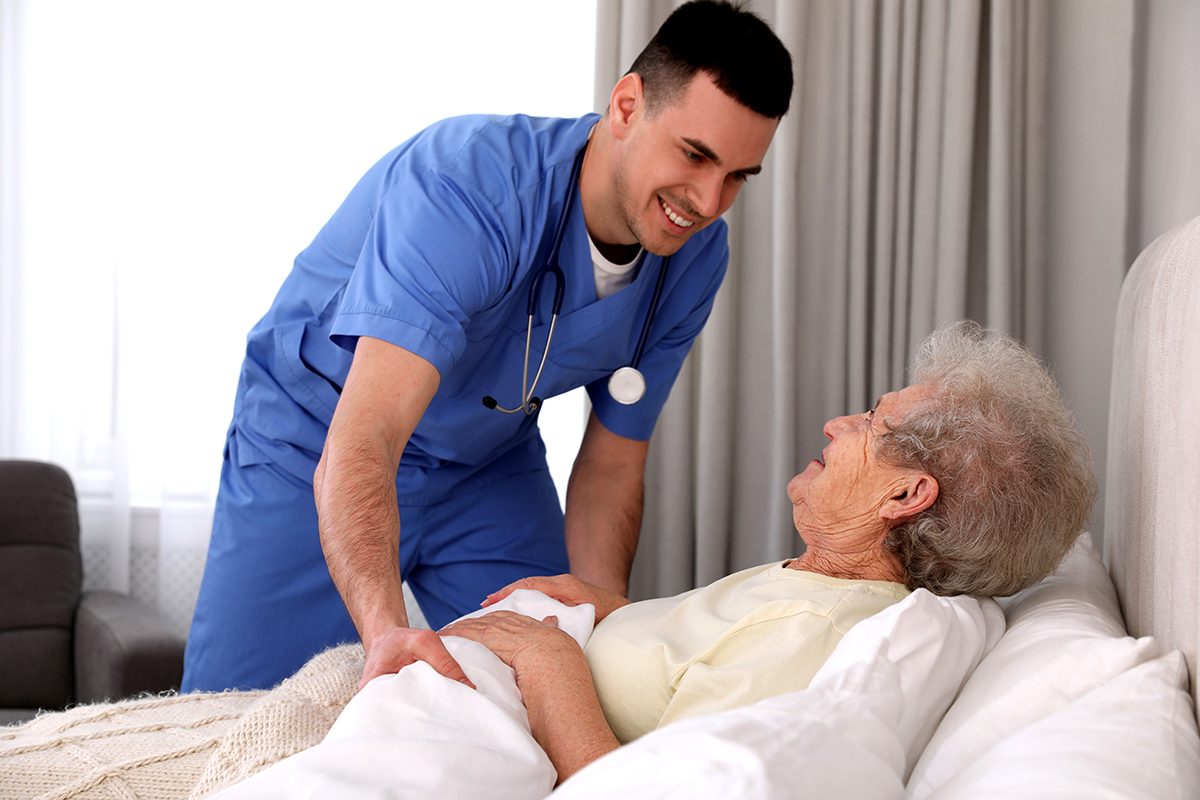 Nurse interacting with elderly woman in bed
