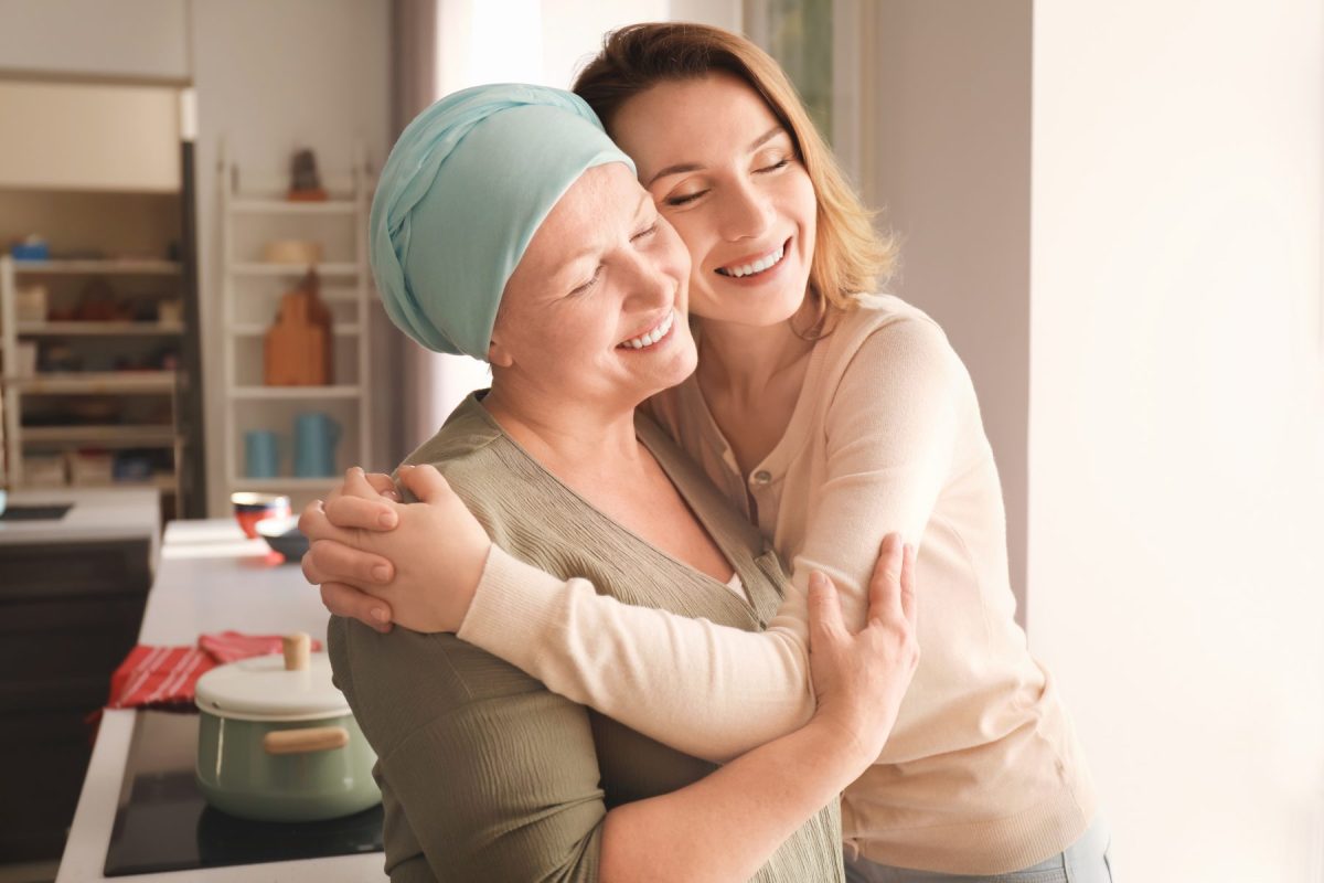 Two women embracing in a bright kitchen setting.