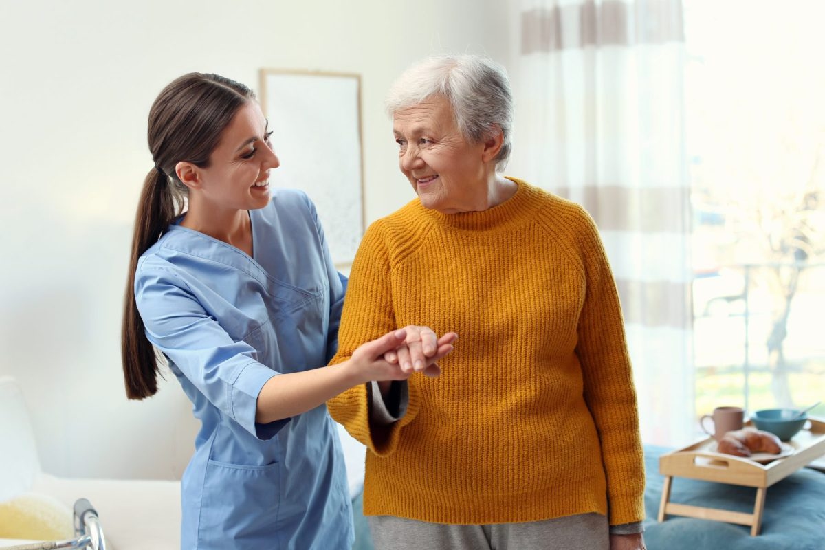 Caregiver assisting a senior woman indoors