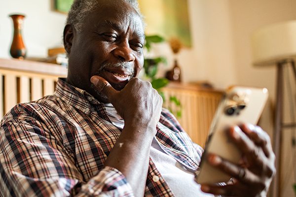 Older man enjoying time on his smartphone in a cozy setting.