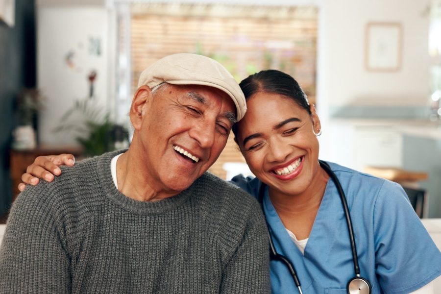 Smiling resident and staff member in a cozy facility setting.