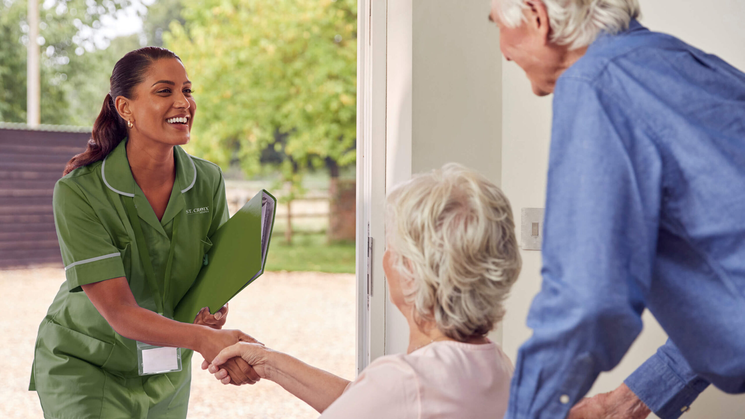 Caregiver greeting two senior residents outside