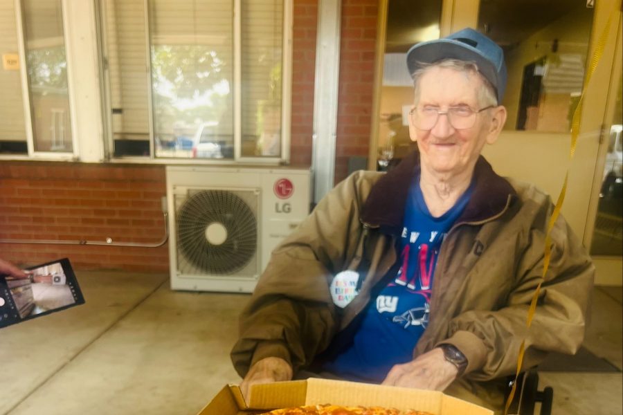 Smiling elderly man enjoying pizza outdoors