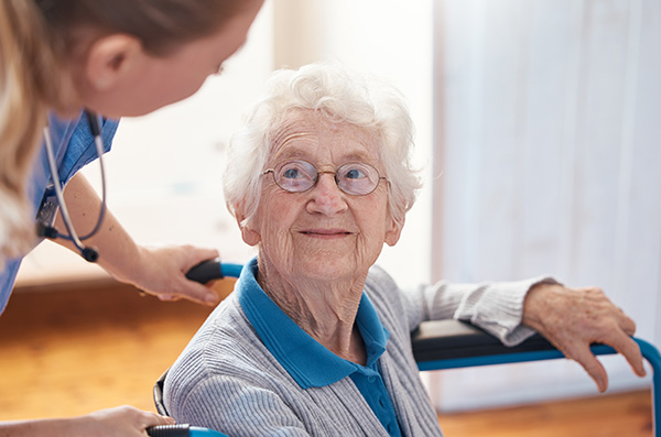 Nurse assisting an elderly woman in a facility