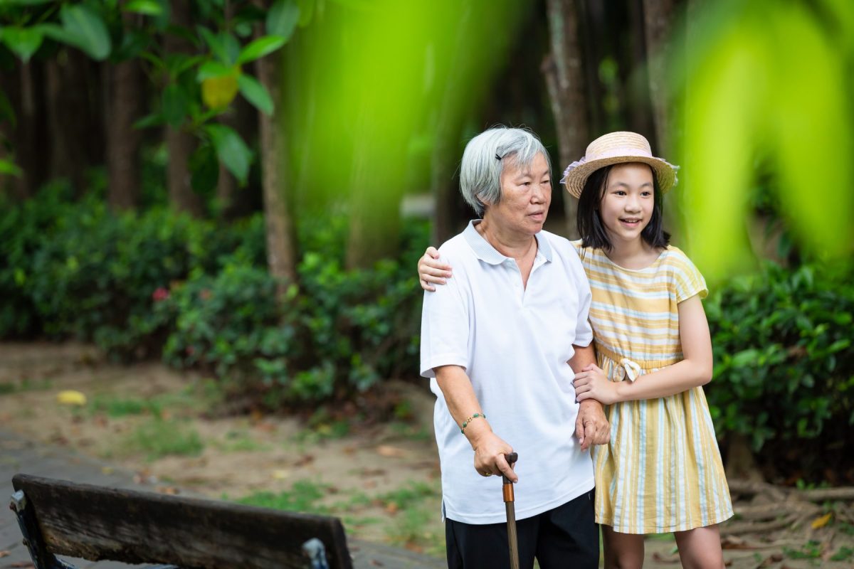 Elderly woman with a young girl in a garden.