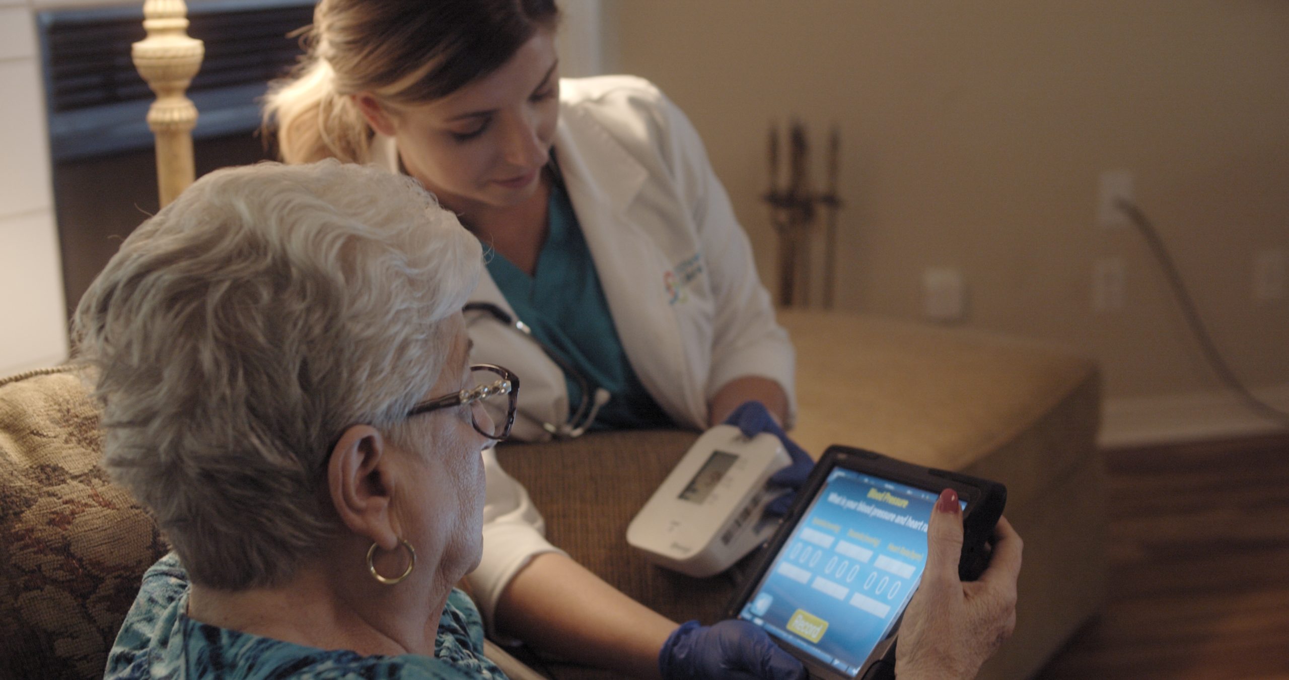 Healthcare staff assisting a resident with a tablet.