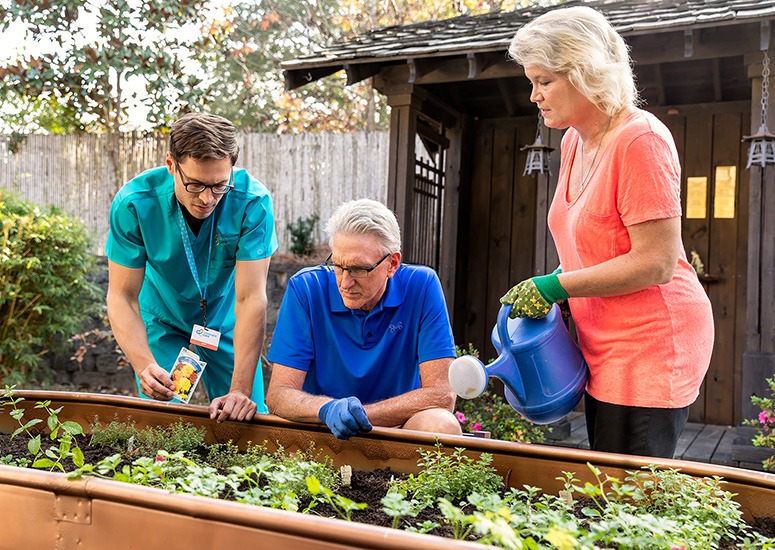 Staff and residents gardening together outdoors.