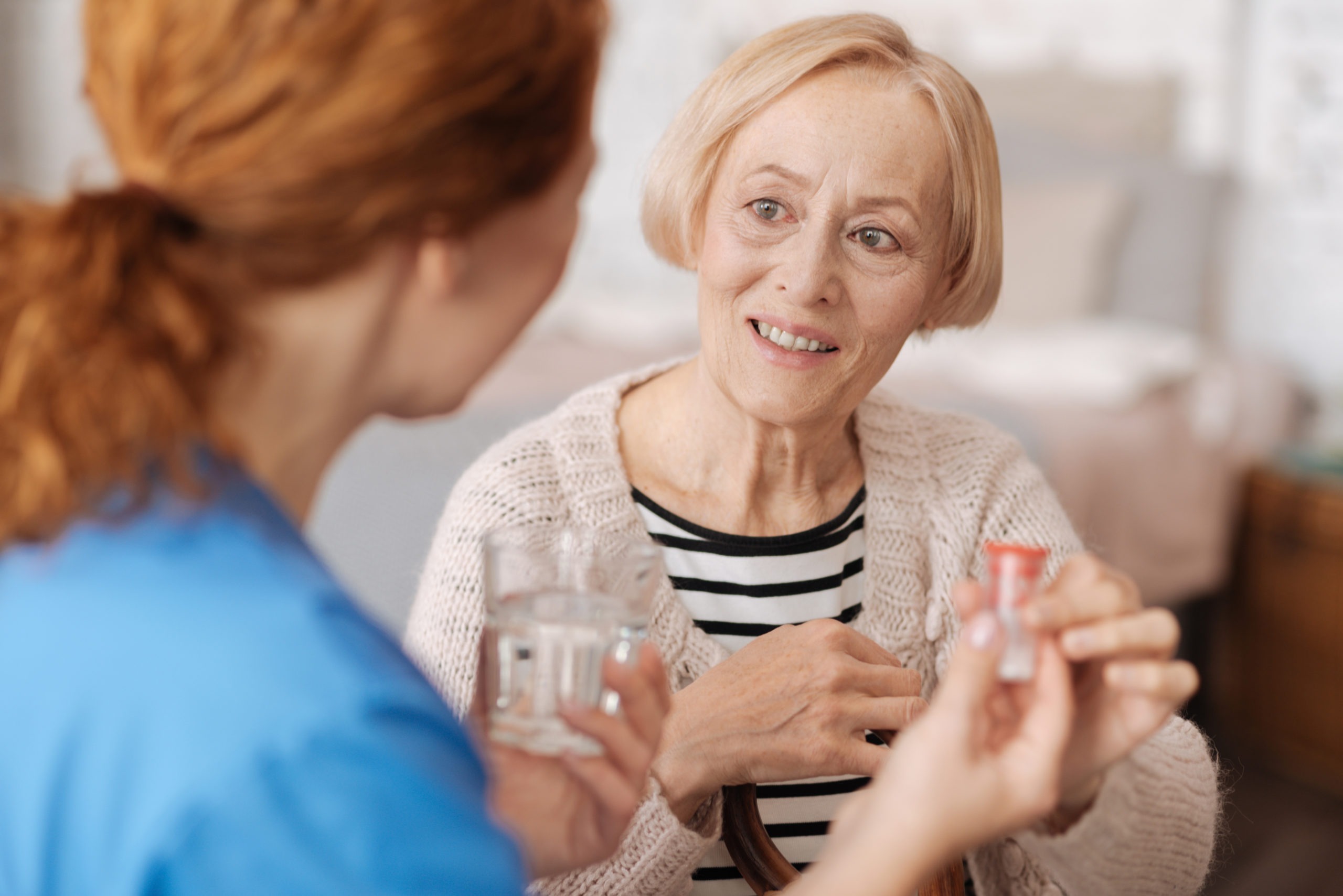 Senior woman receiving medication from caregiver