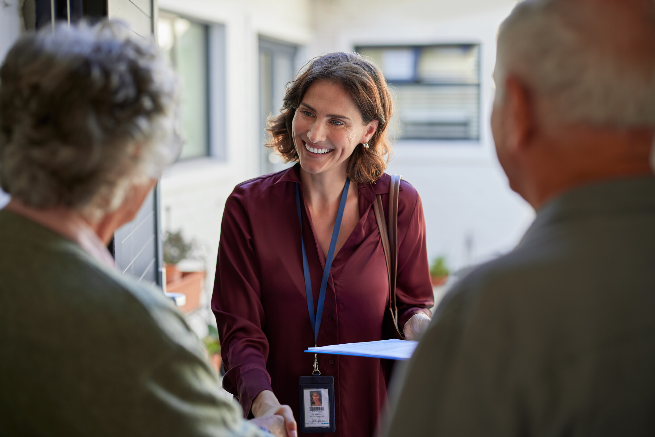 Staff member greeting two elderly residents.