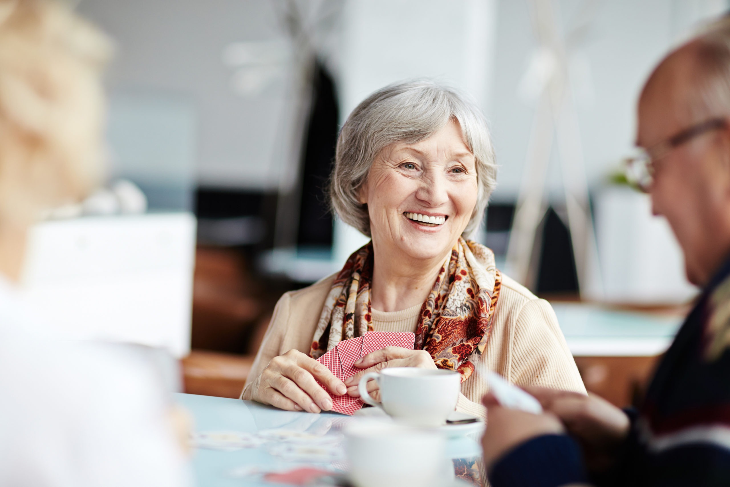 Smiling senior woman enjoying coffee with friends.