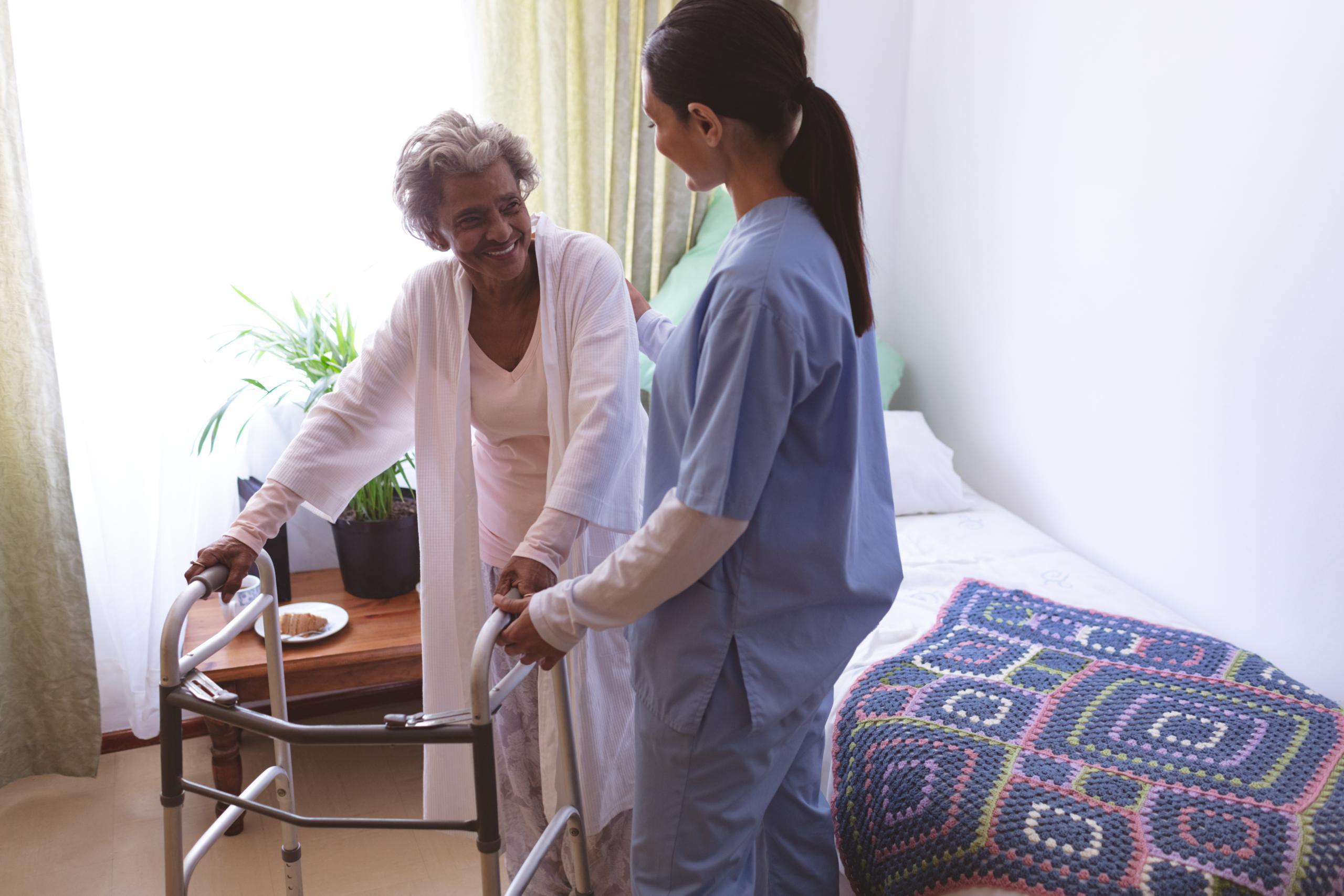 Caregiver assisting a resident with a walker.