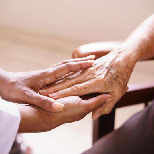 Close-up of caregiver and elderly person's hands.