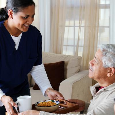 Caregiver serving food to a senior resident
