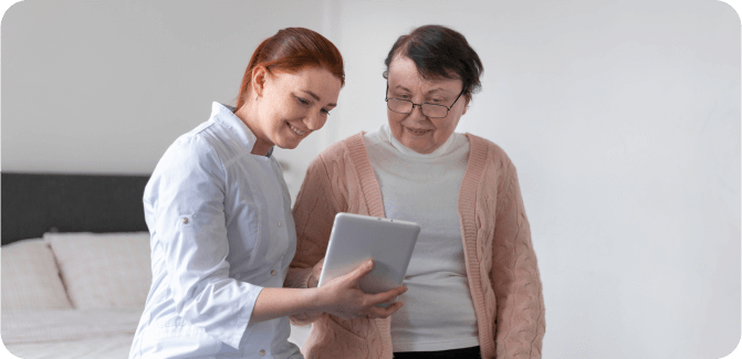 Caregiver assisting an elderly woman with a tablet