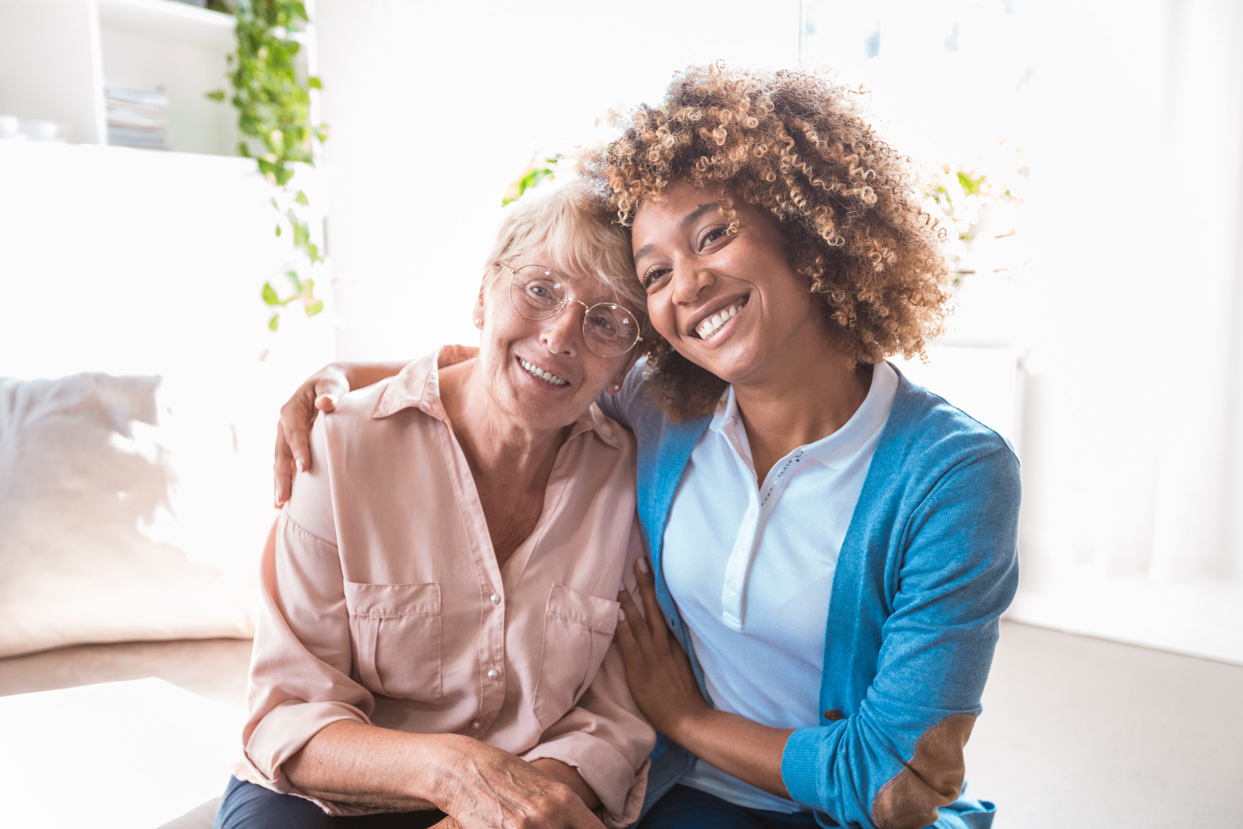 Two women smiling together in a living room.